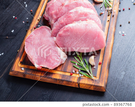 Pork steak, raw carbonate fillet on dark background, meat with rosemary, seasonings, side view Pork steak, raw carbonate fillet on dark background, meat with rosemary, seasonings, side view 89367768