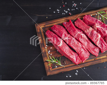 Raw meat, beef steak with seasoning on chopping board on dark background with rosemary, 89367785