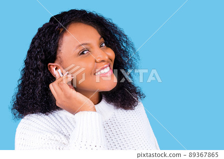 african american woman isolated on blue background in studio Listen music with earpods 89367865
