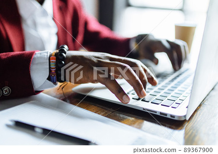 Smiling businessman in a marsala jacket working on laptop computer in office 89367900