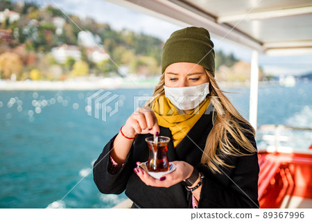 woman drinking masala tea in the front, bosphorus bay in the background woman drinking masala tea in the front, bosphorus bay in the background 89367996