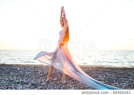 Beautiful long haired woman dressed a mermaid sitting on the sand beach background 89368261