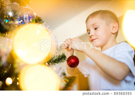 cute blond little boy holding his christmas present at christmas time self-isolation in quarantine due to coronavirus 89368393