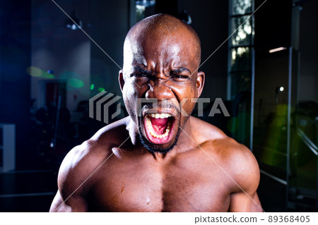 mulatto coach lifting weights over dark background in new gym mulatto coach lifting weights over dark background in new gym 89368405