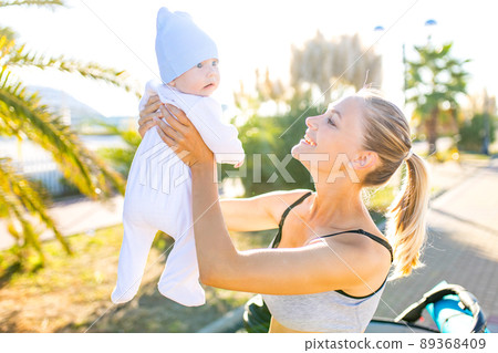 happy blonde woman kissind and feelinf adore to her stroll new born kid in tropics beach park outdoors happy blonde woman kissind and feelinf adore to her stroll new born kid in tropics beach park outdoors 89368409