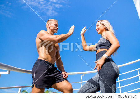 young couple in sport clothing doing stretching exercises together outdoor in summer beach tropics young couple in sport clothing doing stretching exercises together outdoor in summer beach tropics 89368414