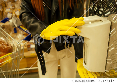 redhaired ginger woman in casual black leather jacket , rubber gloves yellow use antibacterial gel in empty super market second wave redhaired ginger woman in casual black leather jacket , rubber gloves yellow use antibacterial gel in empty super market second wave 89368417