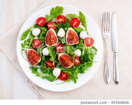 Fresh salad with figs, tomatoes, cucumbers, arugula, mozzarella. Oil with spices, 89368608
