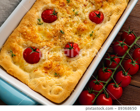 appetizing golden focaccia with tomatoes and spices, on dark wooden rustic table appetizing golden focaccia with tomatoes and spices, on dark wooden rustic table 89368650