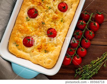 appetizing golden focaccia with tomatoes and spices, on dark wooden rustic table appetizing golden focaccia with tomatoes and spices, on dark wooden rustic table 89368718