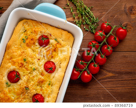 appetizing golden focaccia with tomatoes and spices, on dark wooden rustic table appetizing golden focaccia with tomatoes and spices, on dark wooden rustic table 89368719