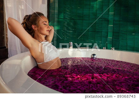 Woman relaxing in round outdoor bath with tropical flowers, organic skin care, luxury spa hotel Valentine's Day alone honeymoon Woman relaxing in round outdoor bath with tropical flowers, organic skin care, luxury spa hotel Valentine's Day alone honeymoon 89368743
