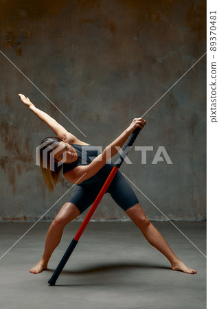 beautiful girl in sports uniform is training kung fu in the studio, fighter athlete, practicing martial arts with a stick beautiful girl in sports uniform is training kung fu in the studio, fighter athlete, practicing martial arts with a stick 89370481