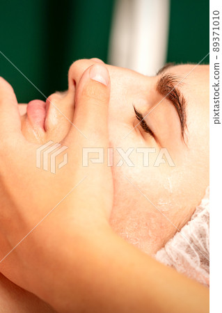 Face massage. Beautiful caucasian young white woman having a facial massage with closed eyes in a spa salon 89371010