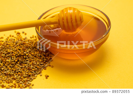 A ladle of honey on the background of a honeycomb of a bee. Honey tidbit in a glass jar honey spoon, bee bread and a honeycomb of wax on a yellow background. Healthy food concept. A ladle of honey on the background of a honeycomb of a bee. Honey tidbit in a glass jar honey spoon, bee bread and a honeycomb of wax on a yellow background. Healthy food concept. 89372055