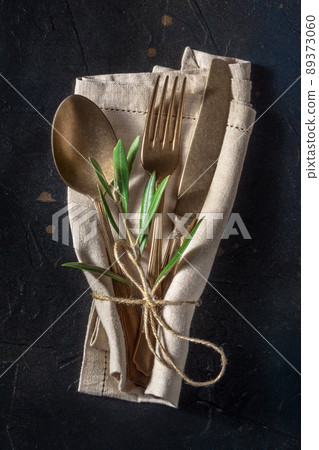 Cutlery. A spoon, a fork, and a knife with an olive branch, on black 89373060