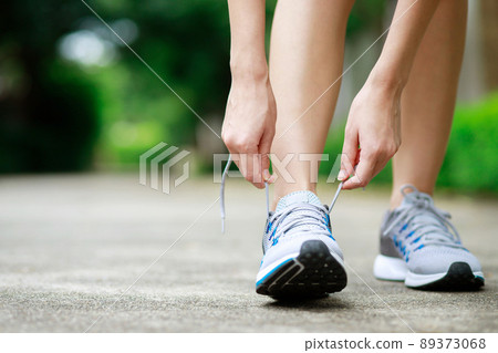 Running shoes. close up female athlete tying laces for jogging on road. Runner ties getting ready for training. Sport lifestyle. copy space banner. 89373068