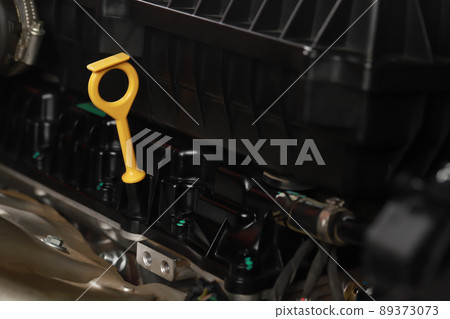 The mechanic is checking the engine oil. The mechanic is checking the engine oil. 89373073