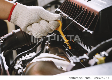 The mechanic is checking the engine oil. The mechanic is checking the engine oil. 89373285