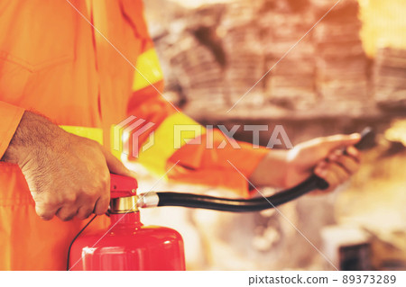 hand presses the trigger fire extinguisher available in fire emergencies conflagration damage background. Safety hand presses the trigger fire extinguisher available in fire emergencies conflagration damage background. Safety 89373289