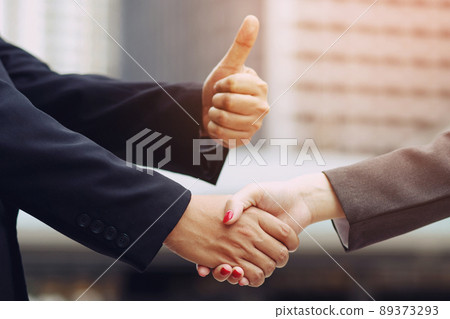 Closeup of a businessman hand shake businesswoman between two colleagues thumbs up Closeup of a businessman hand shake businesswoman between two colleagues thumbs up 89373293