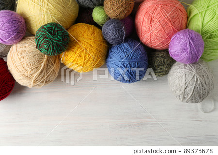 Balls of yarn on white wooden background 89373678
