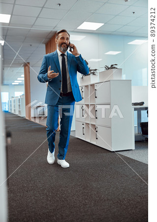 Smiling male manager talking on phone in the office space Smiling male manager talking on phone in the office space 89374212