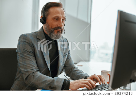 Smiling man is busy while speaking online Smiling man is busy while speaking online 89374213