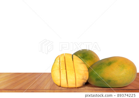 Ripe mangoes on a wooden table with a white background. Ripe mangoes on a wooden table with a white background. 89374225