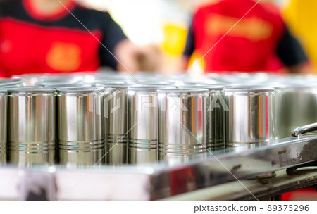 Many cans on blur workers. Canned fish factory. Food industry. Workers working in canned food factories to fill sardines in tinned cans. Food processing production line. Food manufacturing industry. 89375296