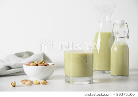 Pistachio milk in glass, lactose free. Vegan nutty plant based milk. Pistachio milk in glass, lactose free. Vegan nutty plant based milk. 89376100