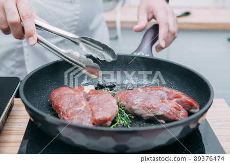 Cooking beef ribeye steak in a frying pan in the cooking class. Steak with spices. Cooking process, close-up. Cooking beef ribeye steak in a frying pan in the cooking class. Steak with spices. Cooking process, close-up. 89376474