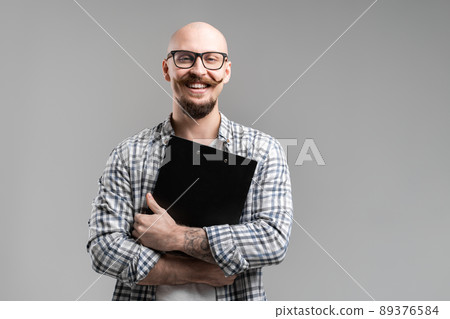 Handsome balded beard with musctache man wearing casual clothes holding clipboard smiling isolated over gray background. Handsome balded beard with musctache man wearing casual clothes holding clipboard smiling isolated over gray background. 89376584
