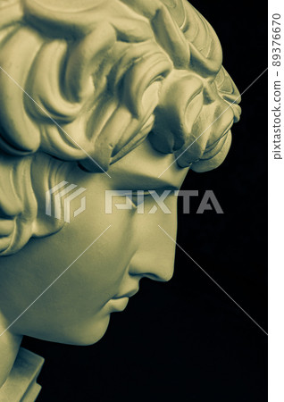 Bronze color gypsum copy ancient statue Antinous head lover of Roman Emperor Hadrian for artists on black background. Plaster sculpture of man face. Template art design dj, fashion, poster. Profile. 89376670