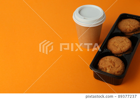 Cookies and paper cup of coffee on orange background 89377237