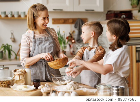 Happy woman and cute children cooking together in kitchen Happy woman and cute children cooking together in kitchen 89377563