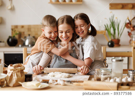 Positive family loving mother and cute children cooking together Positive family loving mother and cute children cooking together 89377586