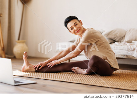 Mature female stretching on floor in morning Mature female stretching on floor in morning 89377614