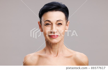 Middle aged female's face against gray background 89377617