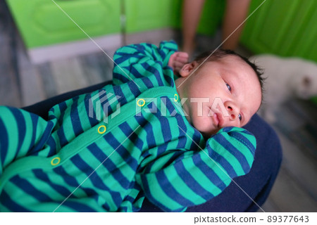 Infant baby in striped clothes lies with arms raised up Infant baby in striped clothes lies with arms raised up 89377643