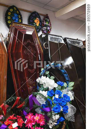 Inside the funeral service store are wooden coffins and wreaths with sparkling flowers Inside the funeral service store are wooden coffins and wreaths with sparkling flowers 89378989
