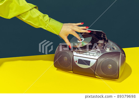 Colorful image of vintage radio player on bright yellow tablecloth isolated over dark green background. Putting music disk Colorful image of vintage radio player on bright yellow tablecloth isolated over dark green background. Putting music disk 89379698