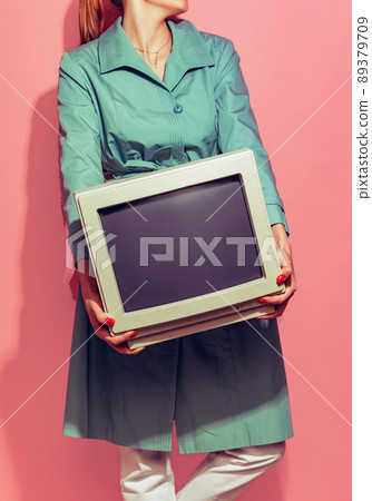 Colorful image of woman holding retro computer monitor isolated over light pink background Colorful image of woman holding retro computer monitor isolated over light pink background 89379709