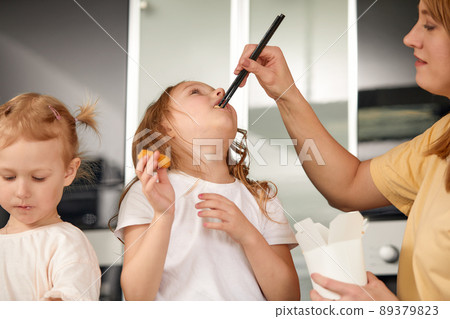 Beautiful caucasian mom and daughter eating rolls and sushi at family lunch at home. Delivery food. Traditional japanese food. 89379823