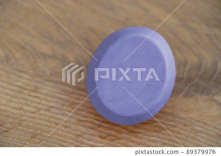 On the wooden table is a purple keychain. On the wooden table is a purple keychain. 89379976