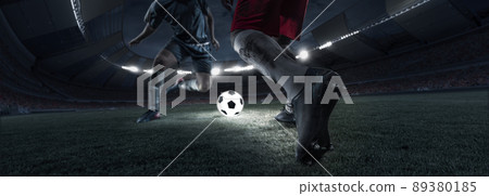 Cropped image of two soccer, football players in motion, action at stadium during football match in evening. Concept of sport, competition, goals Cropped image of two soccer, football players in motion, action at stadium during football match in evening. Concept of sport, competition, goals 89380185
