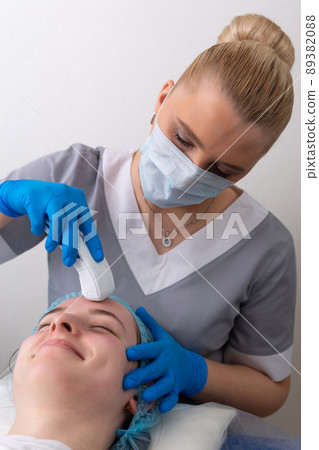Young woman receiving electric galvanic anti-aging face spa massage at beauty salon. 89382088