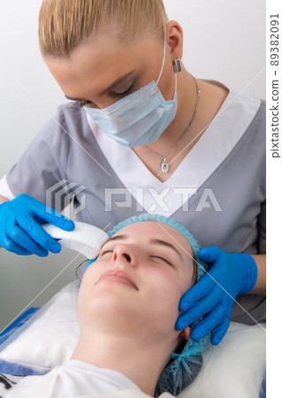 Young woman receiving electric galvanic anti-aging face spa massage at beauty salon. Young woman receiving electric galvanic anti-aging face spa massage at beauty salon. 89382091