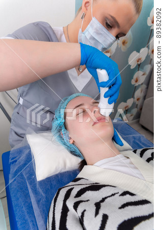 Young woman receiving electric galvanic anti-aging face spa massage at beauty salon. Young woman receiving electric galvanic anti-aging face spa massage at beauty salon. 89382092