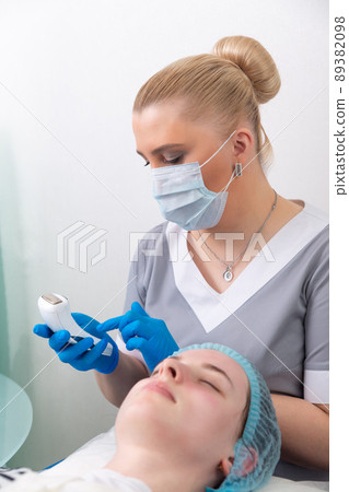 The cosmetologist adjusts the power of the device for galvanic massage. The cosmetologist adjusts the power of the device for galvanic massage. 89382098